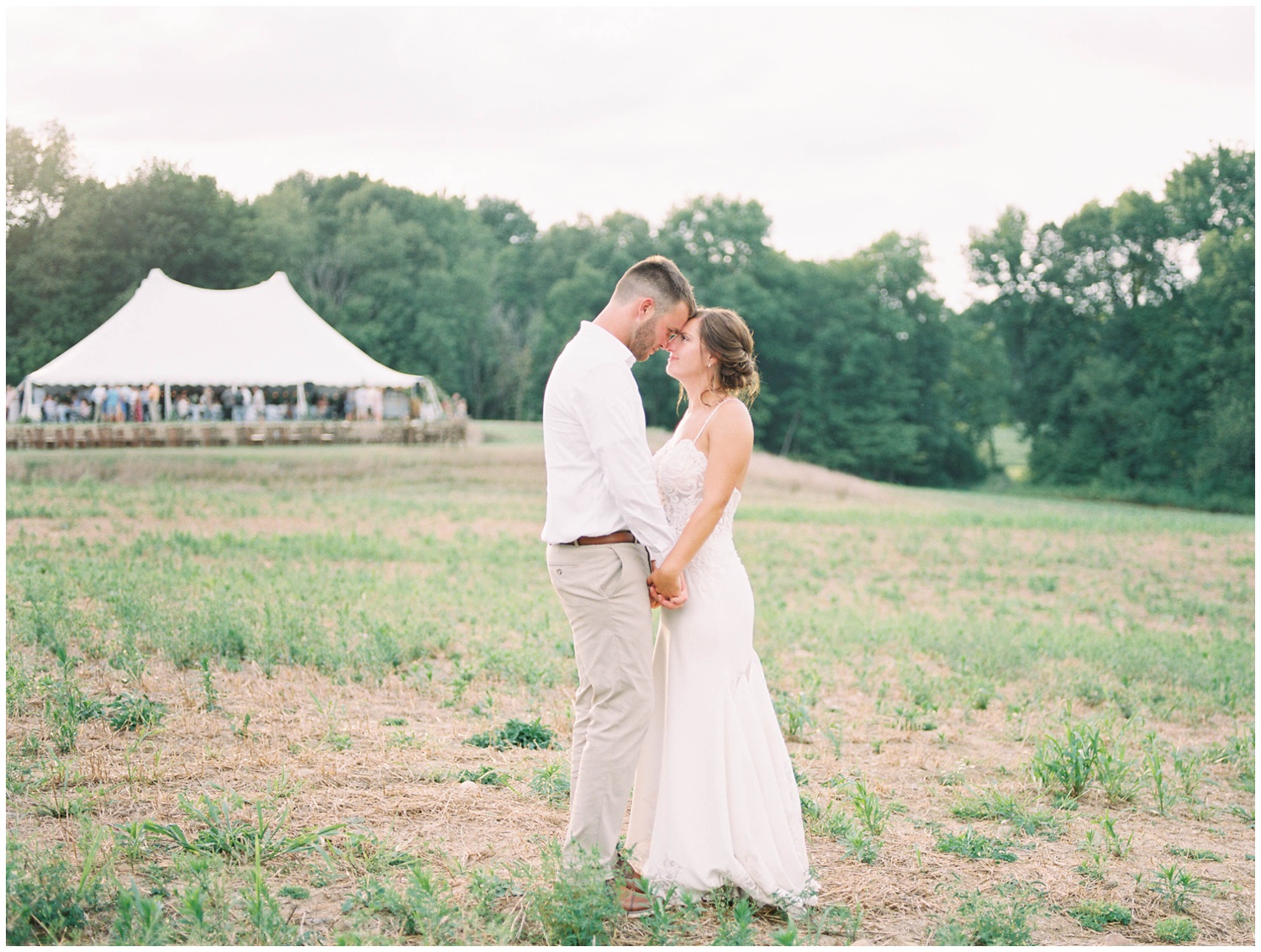 Bride and groom pose in front of their tented backyard wedding in Michigan image by Grand Rapids Wedding Photographer Cynthia Boyle