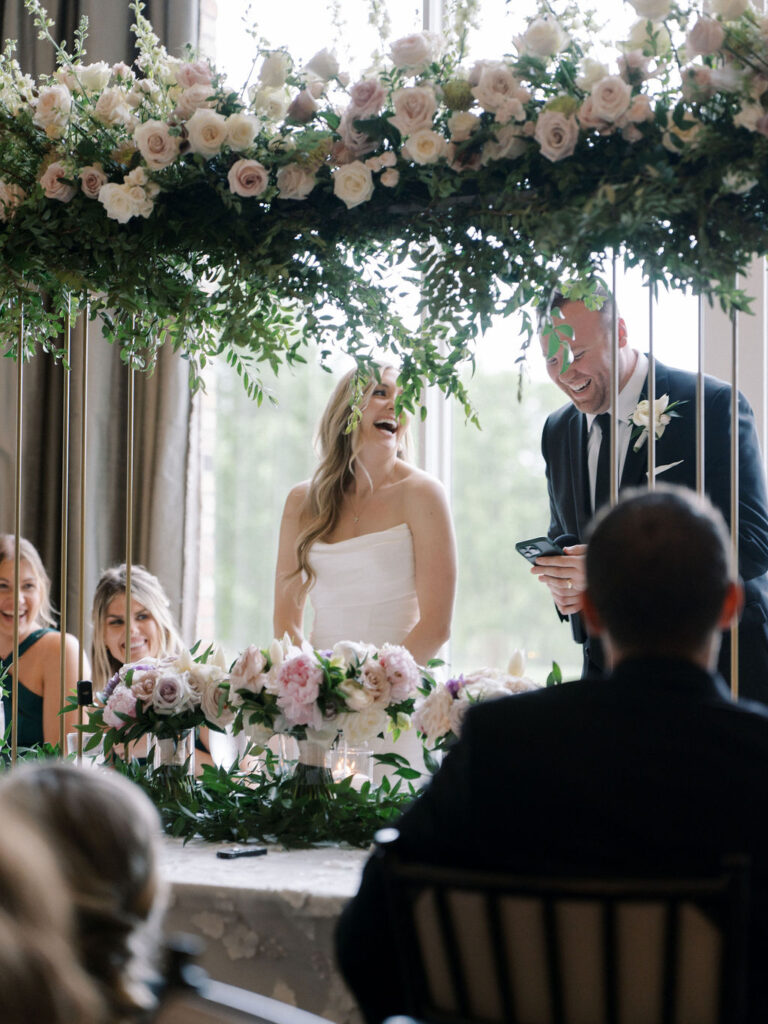 Bride and groom laughing as they give a speech during their reception