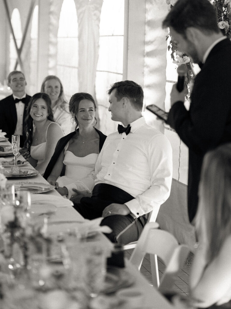Bride and groom smiling at each other during speeches