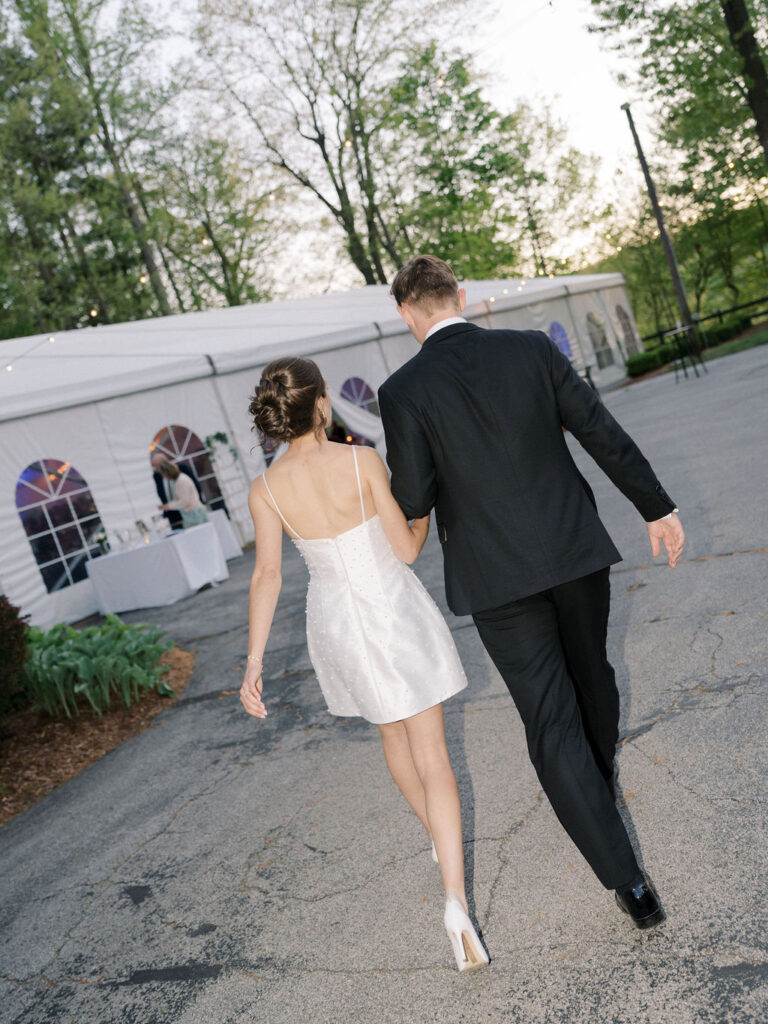 Flash wedding photo of a bride and groom walking back to their tented wedding reception