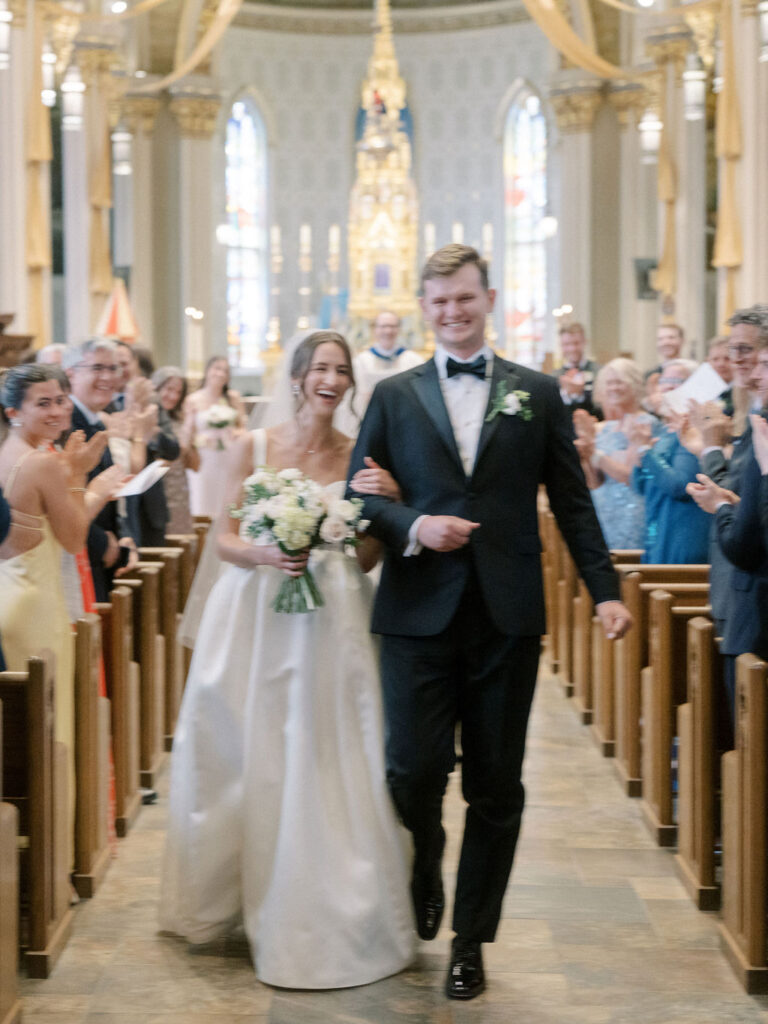 Bride and groom walking back down the aisle as husband and wife during their Notre Dame Basilica wedding ceremony