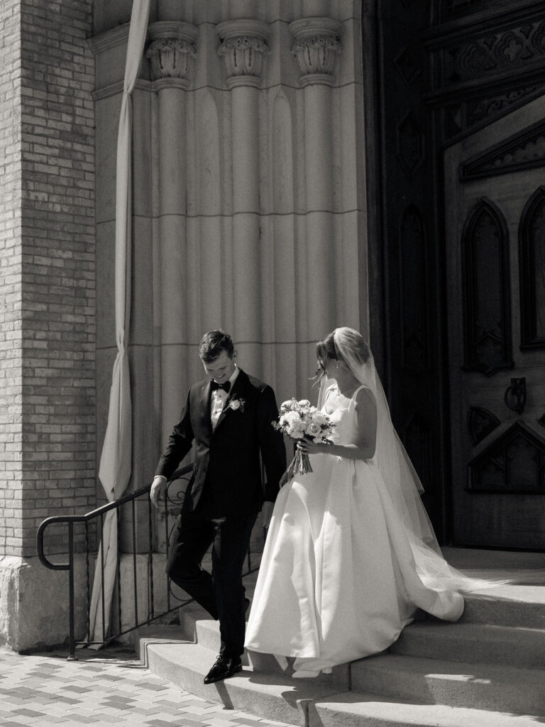 Black and white photo of a bride and groom walking out of their Notre Dame Basilica wedding ceremony as husband and wife
