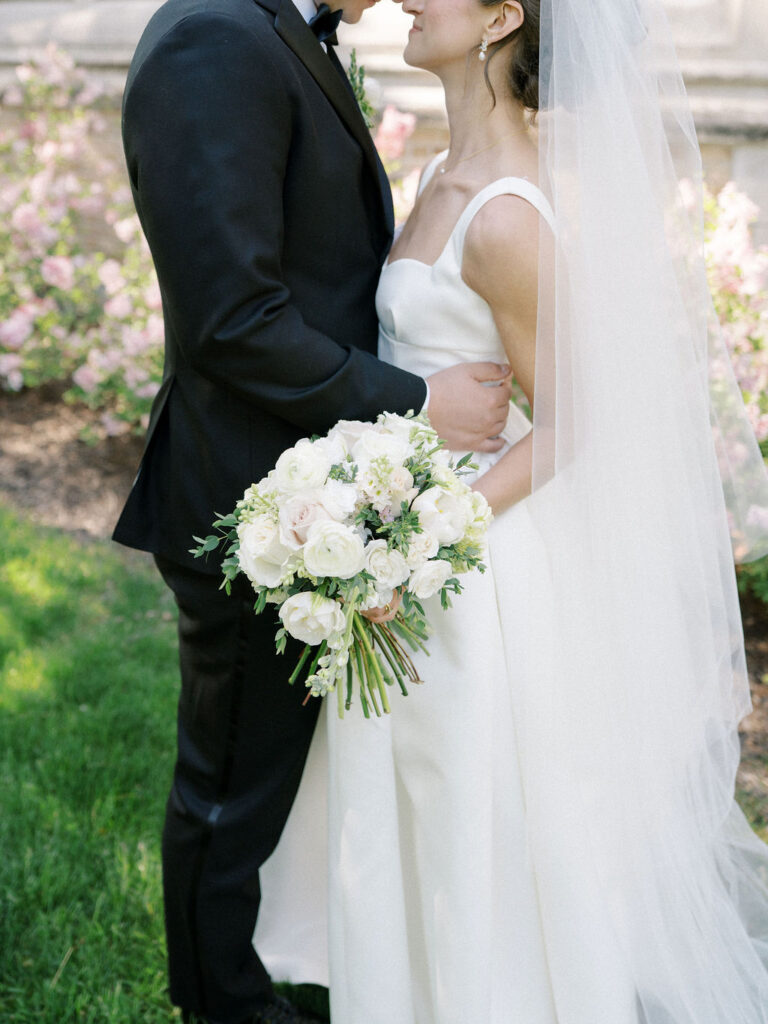 Close-up of the couple holding each other, bride smiling with bouquet in hand for their Notre Dame wedding photos