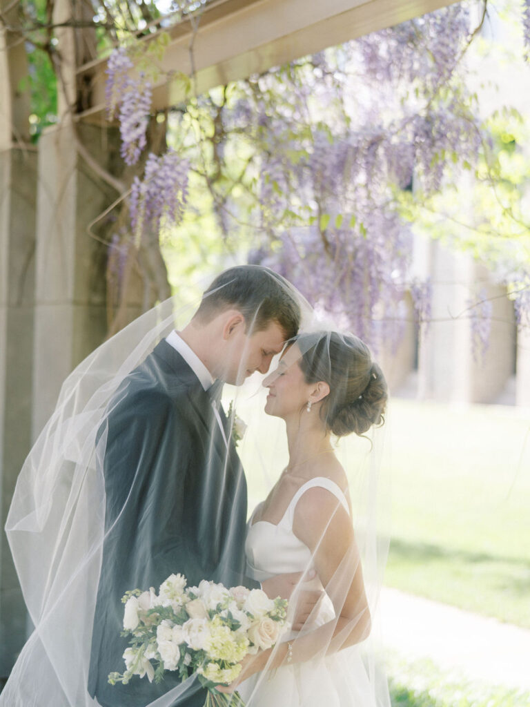 Romantic close-up of the couple draped under the brides veil for their Notre Dame wedding photos