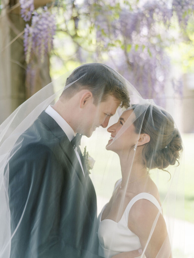 Romantic close-up of the couple draped under the brides veil for their Notre Dame wedding photos
