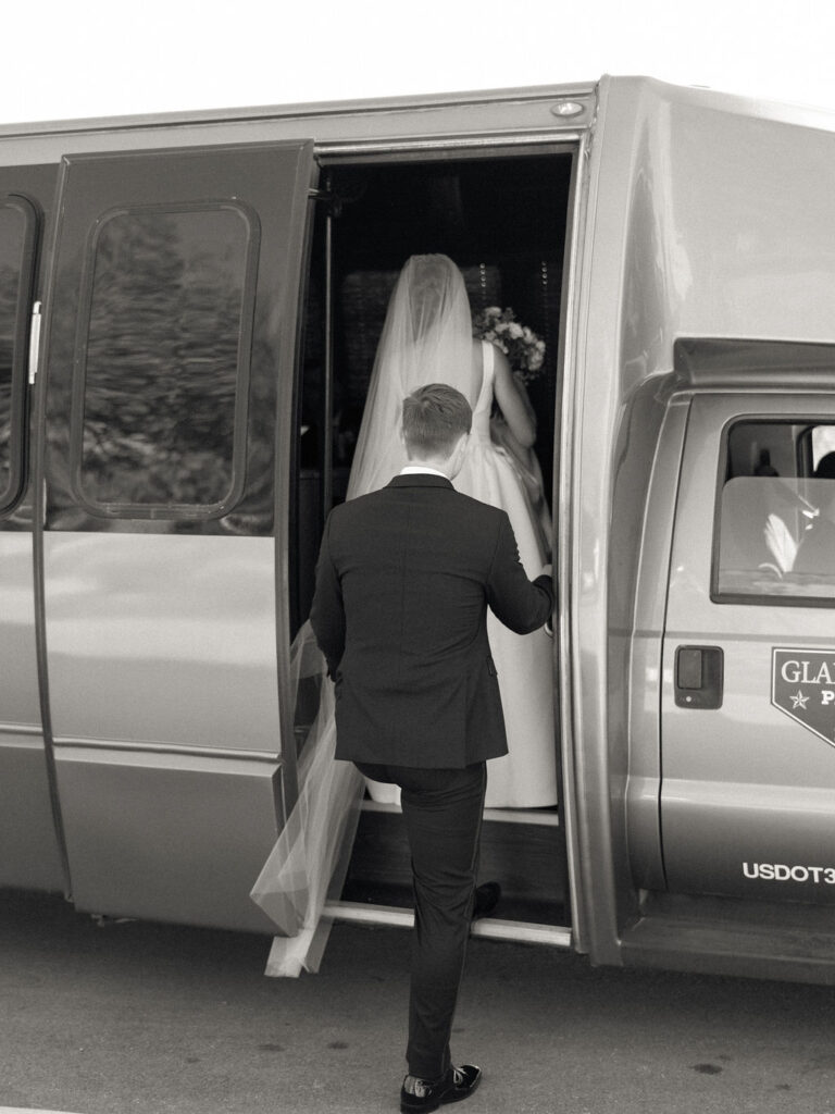 Black and white photo of a bride and groom getting onto a bus