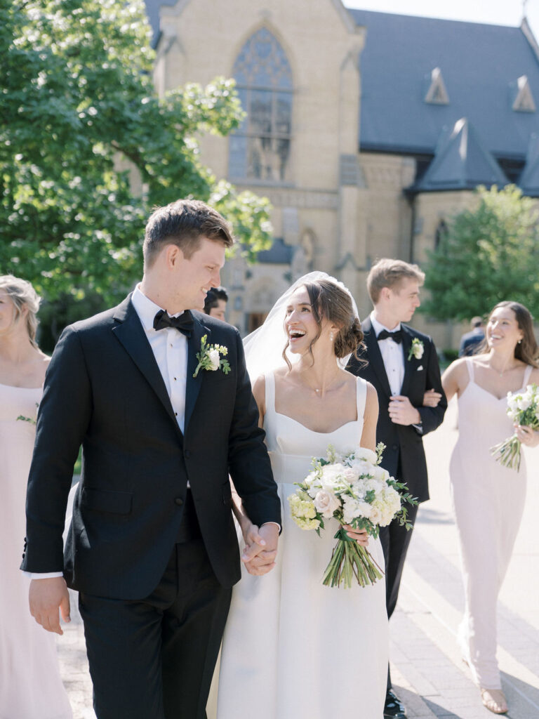 Bride and groom smiling at each other during their outdoor Notre Dame wedding party photo
