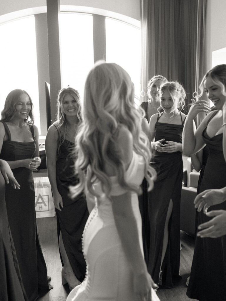 Black and white photo of a bride and her bridesmaids sharing a first look