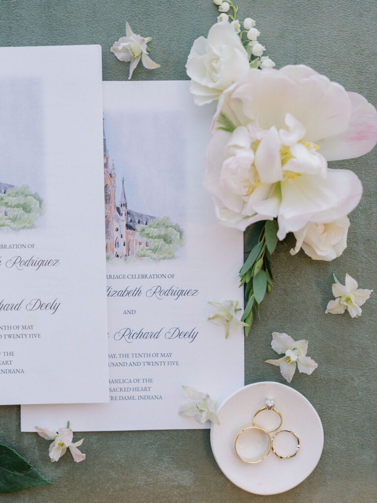 Flat lay of wedding invitation suite and details with blush and floral accents for a Notre Dame wedding