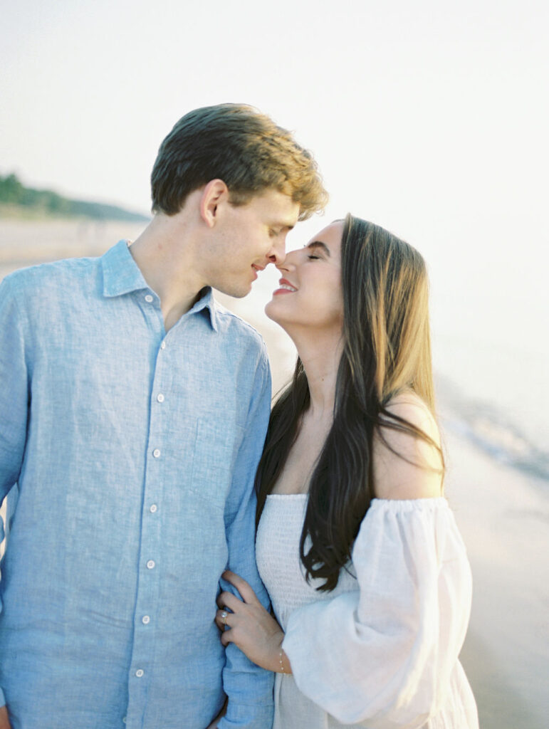 Film engagement photo of a couple touching noses during their session at Warren Dunes State Park in Michigan