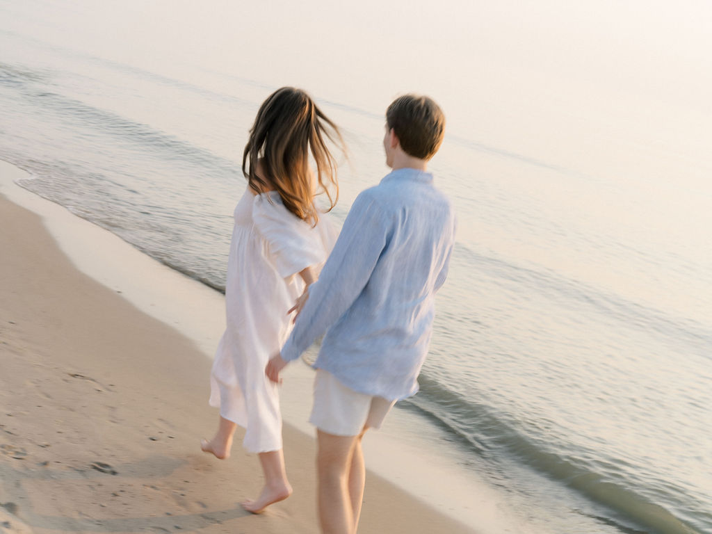 Couple running alone the shoreline at Warren Dunes State Park for their Michigan engagement photos