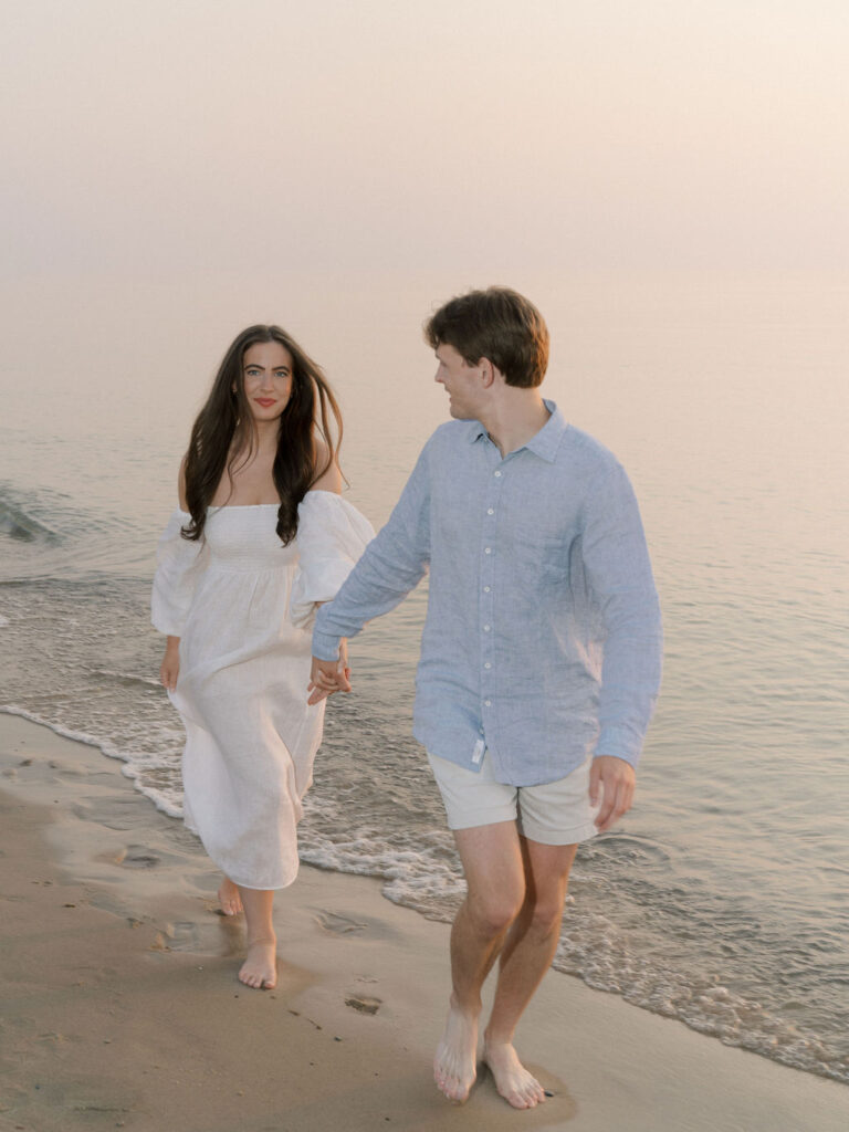 Flash engagement photo of a couple running along the shoreline at Warren Dunes State Park in Michigan
