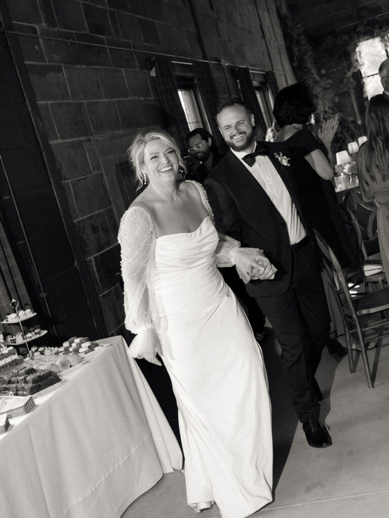 Black and white photo of a bride and groom entering their wedding reception