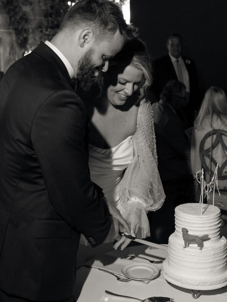 Black and white photo of a bride and groom cutting into their wedding cake