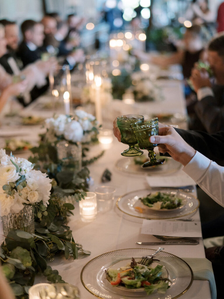 Candid wedding reception photo of guests toasting with vintage drinkware