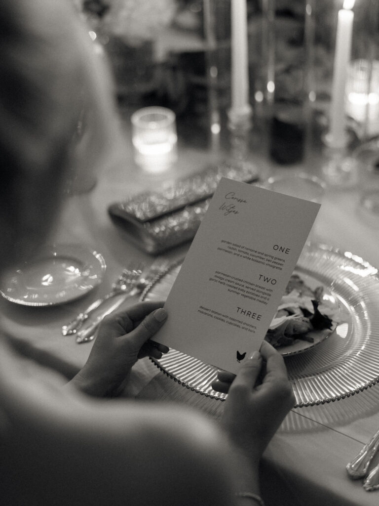 Candid black and white photo of a guest reading the wedding reception dinner menu