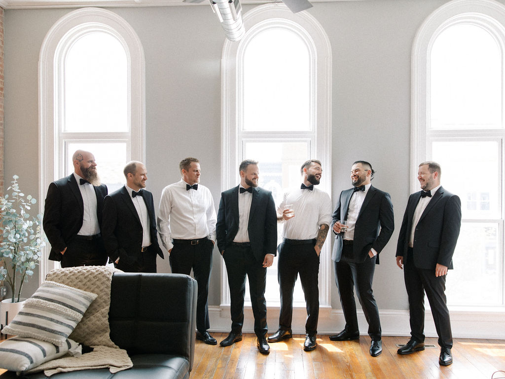 Candid photo of the groom and his groomsmen laughing and having drinks
