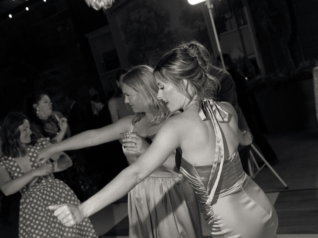 Black and white candid wedding reception photo of guests dancing