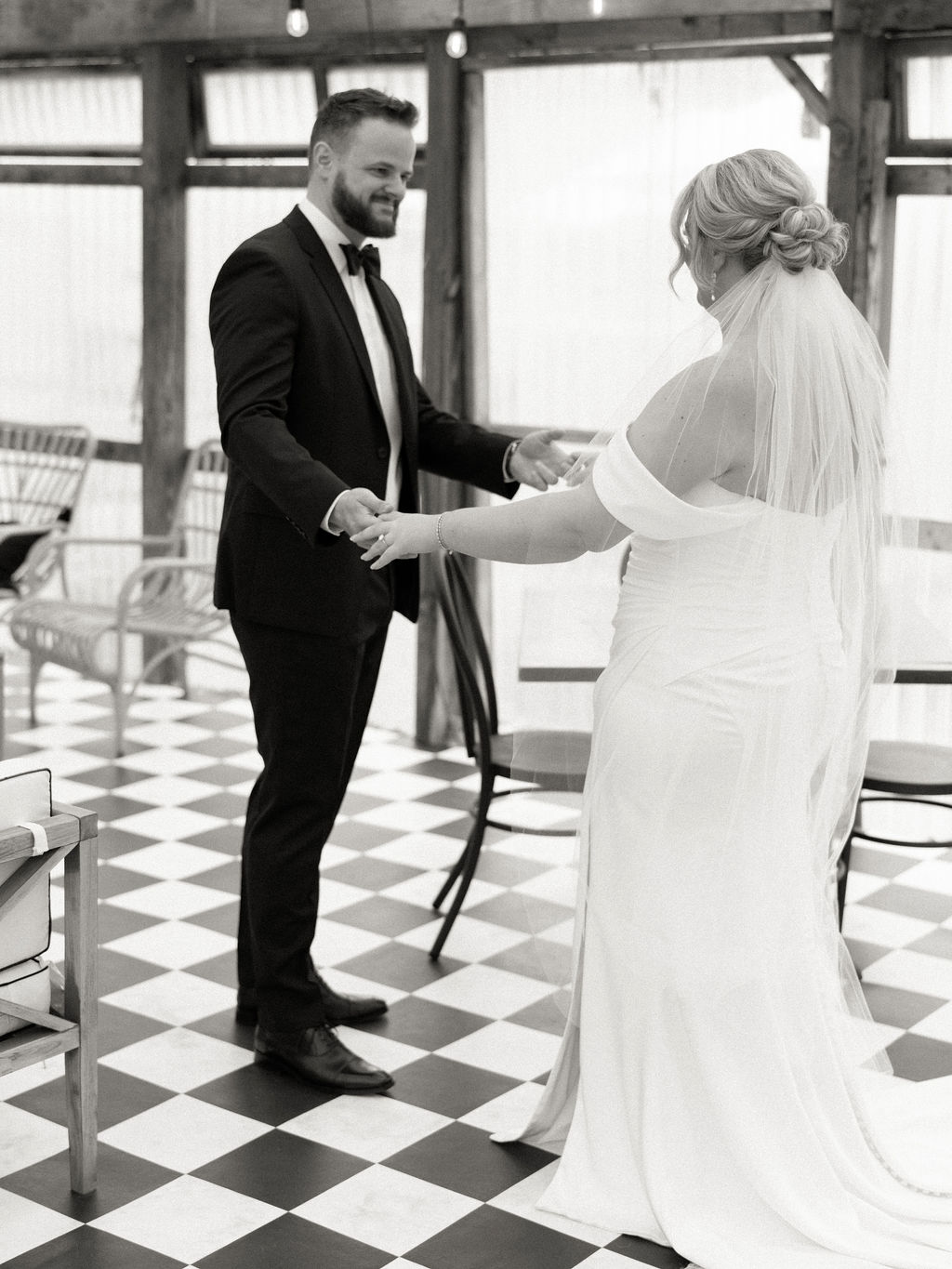 Black and white photo of a groom admiring his bride during their first look in The Greenhouse at The Millhaven