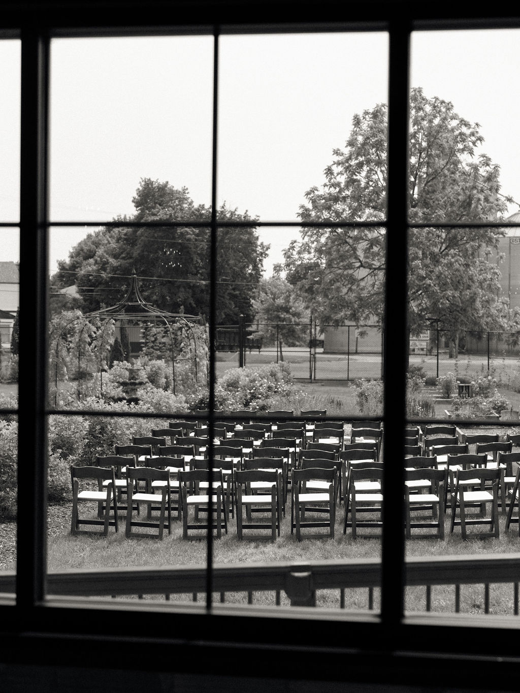 Black and white documentary style photo of an outdoor wedding ceremony setup in the gardens at The Millhaven