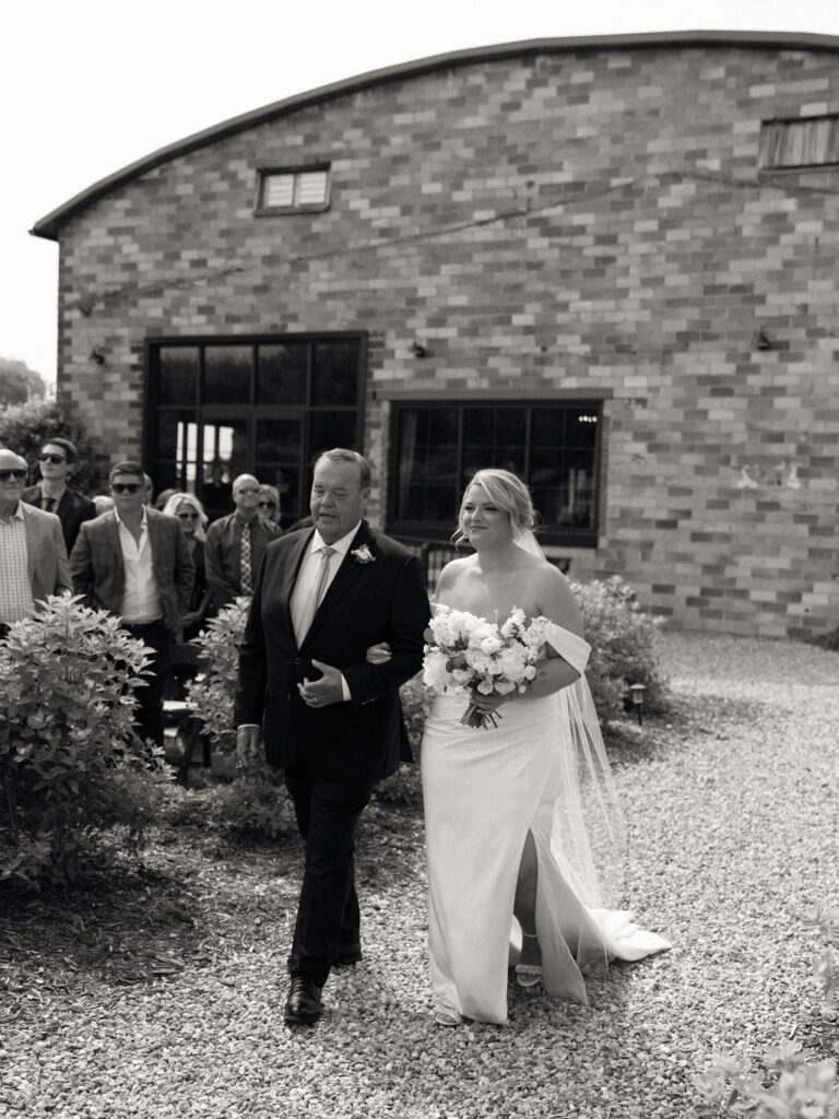 Black and white photo of a bride walking down the aisle with her father