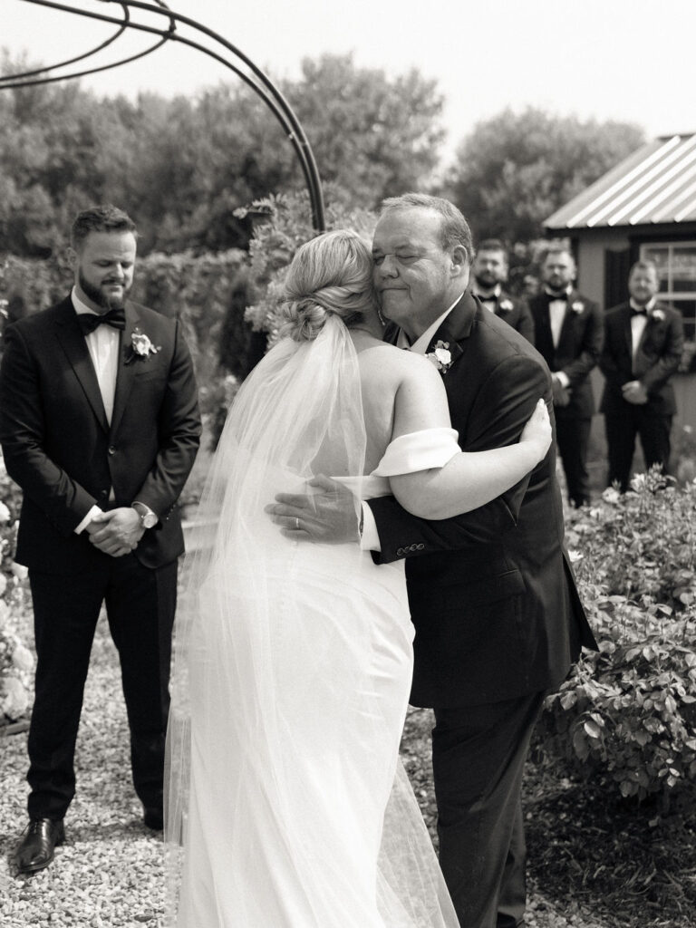 Black and white photo of the bride hugging her father at the end of the aisle