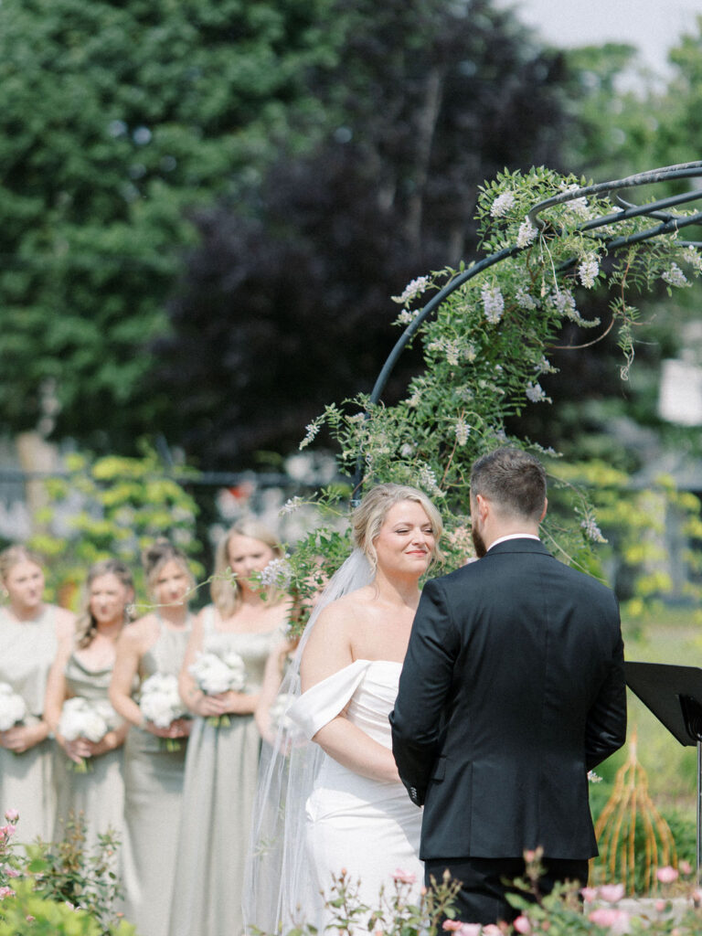 Bride and groom hoding hands during their outdoor garden wedding ceremony at The Millhaven