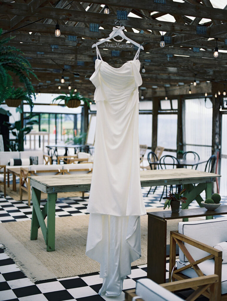 Brides wedding dress hanging in The Greenhouse at The Millhaven