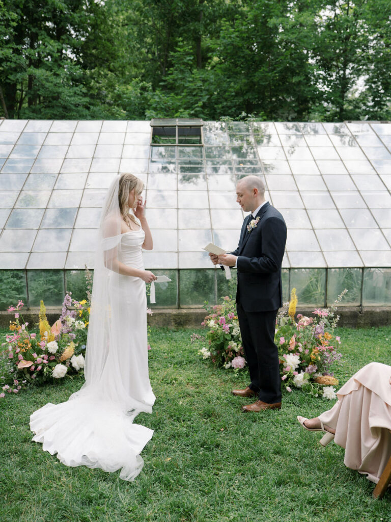 Bride and groom exchanging vows during their outdoor ceremony at The Glass House Community.