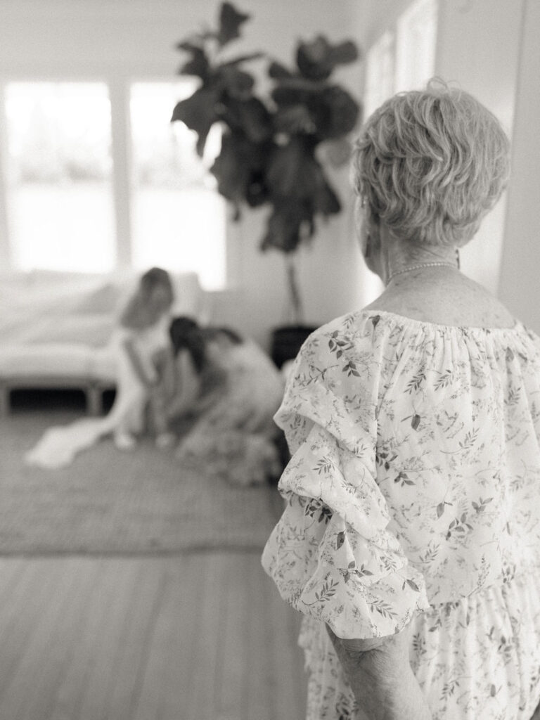 Candid black and white photo of a brides grandmother watching her get ready for her wedding