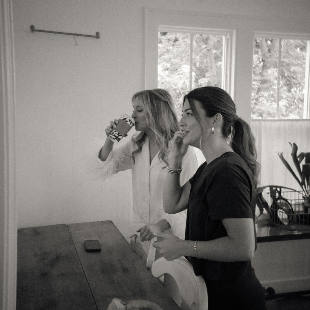Bride and bridesmaid laughing while getting ready at The Glass House Community.