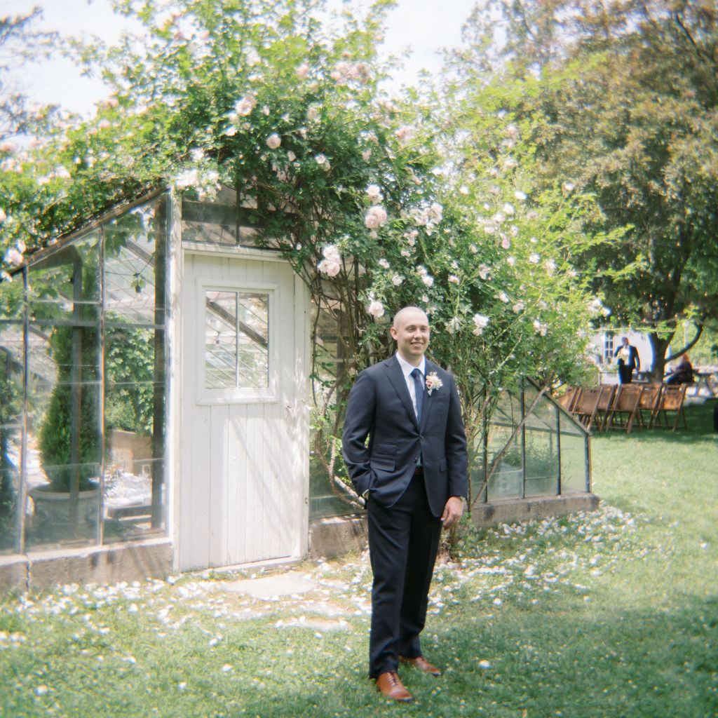 Outdoor grooms portraits in front of the Greenhouse from a Glass House Community wedding in Michigan