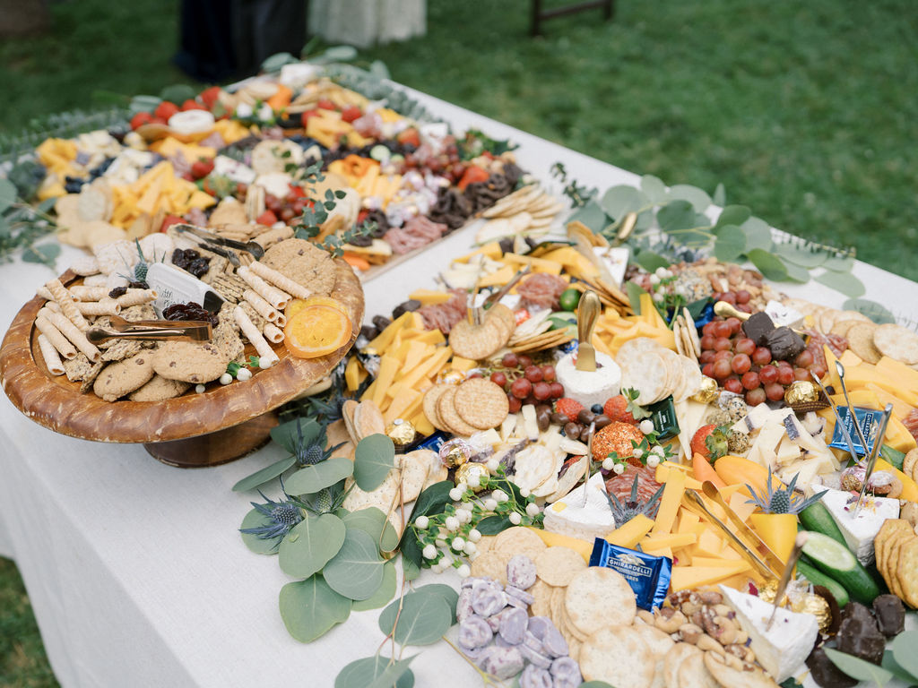 Large grazing table filled with cheese, fruit, crackers, and desserts by Partage Catering.