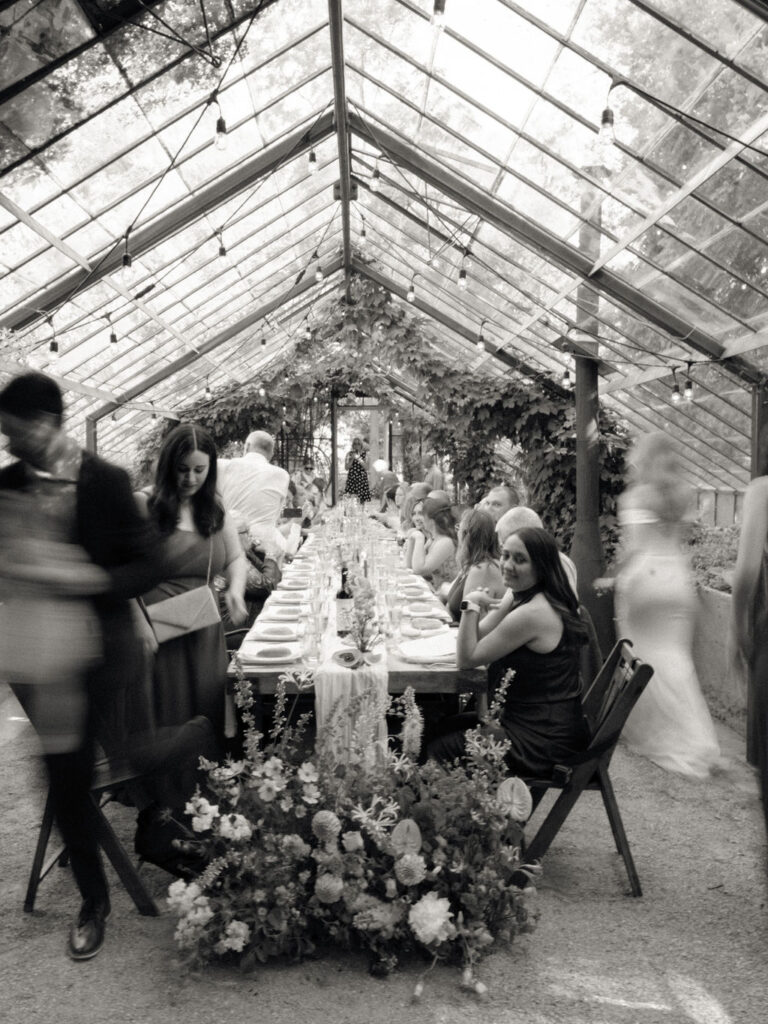 Black and white in motion picture of guests walking around during the reception