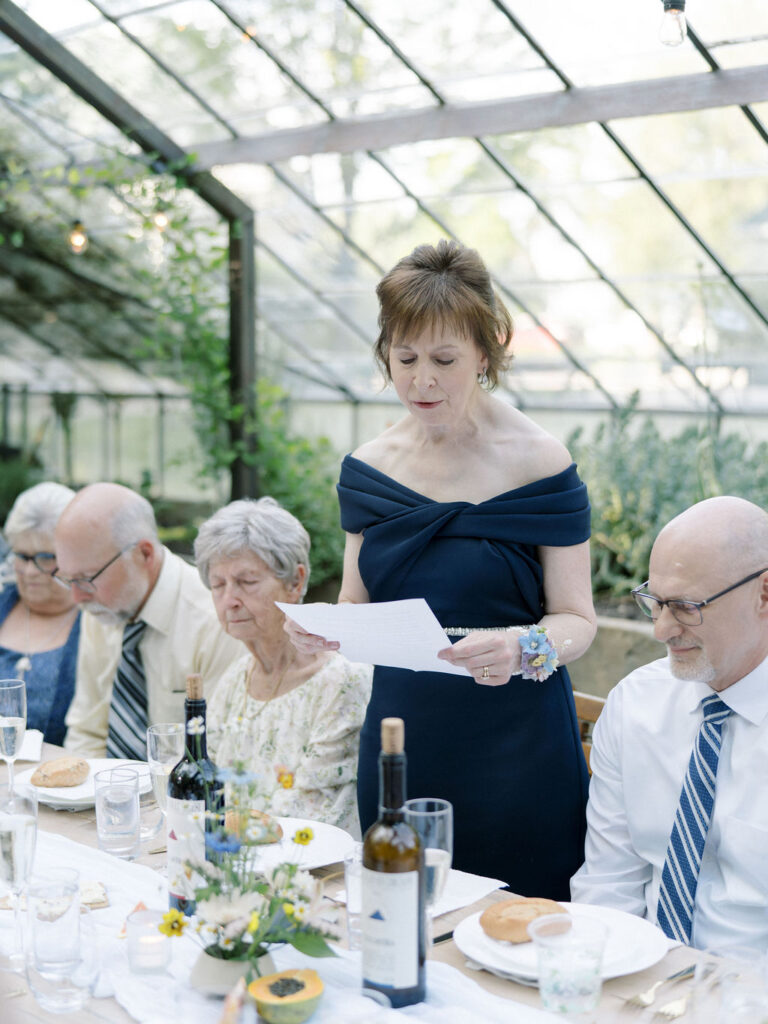 Guest giving a speech during a Glass House Community wedding reception in the greenhouse