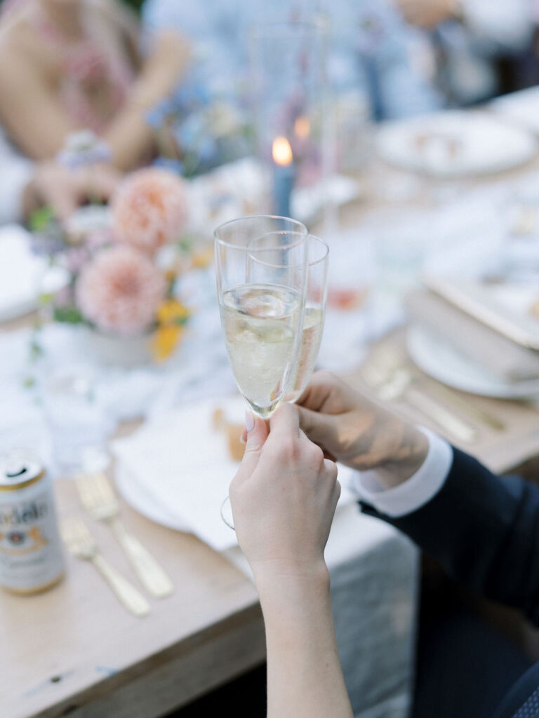 Bride and groom raising a toast with guests during cocktail hour outdoors.