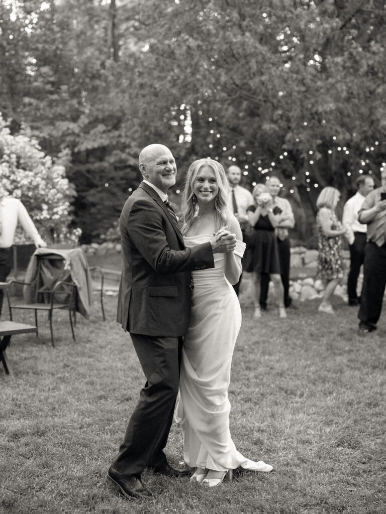 Black and white photo of the bride dancing with her father during her Glass House Community wedding reception