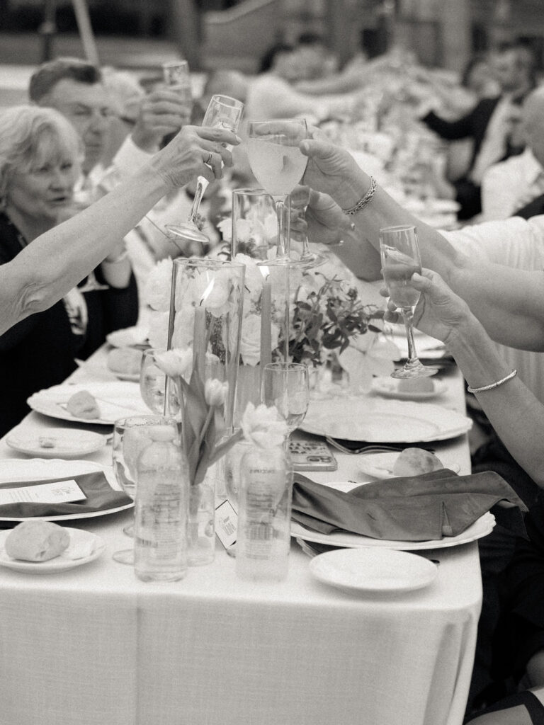 Candid black and white photo of guests toasting their drinks