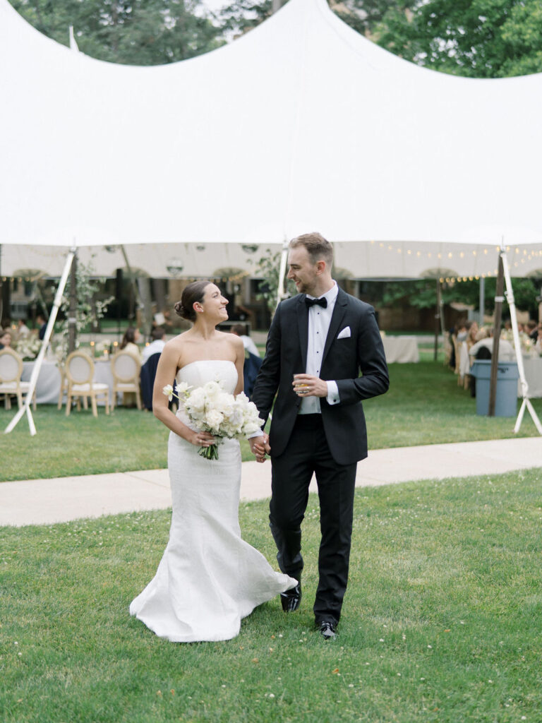 Bride and groom posing in front of their tented Saint Mary’s Notre Dame wedding reception setup behind Le Mans Hall