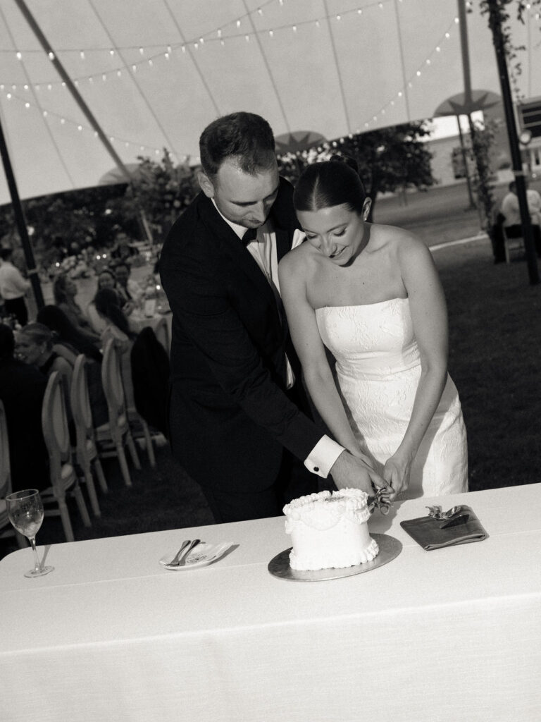 Black and white photo of a bride and groom cutting into their wedding cake