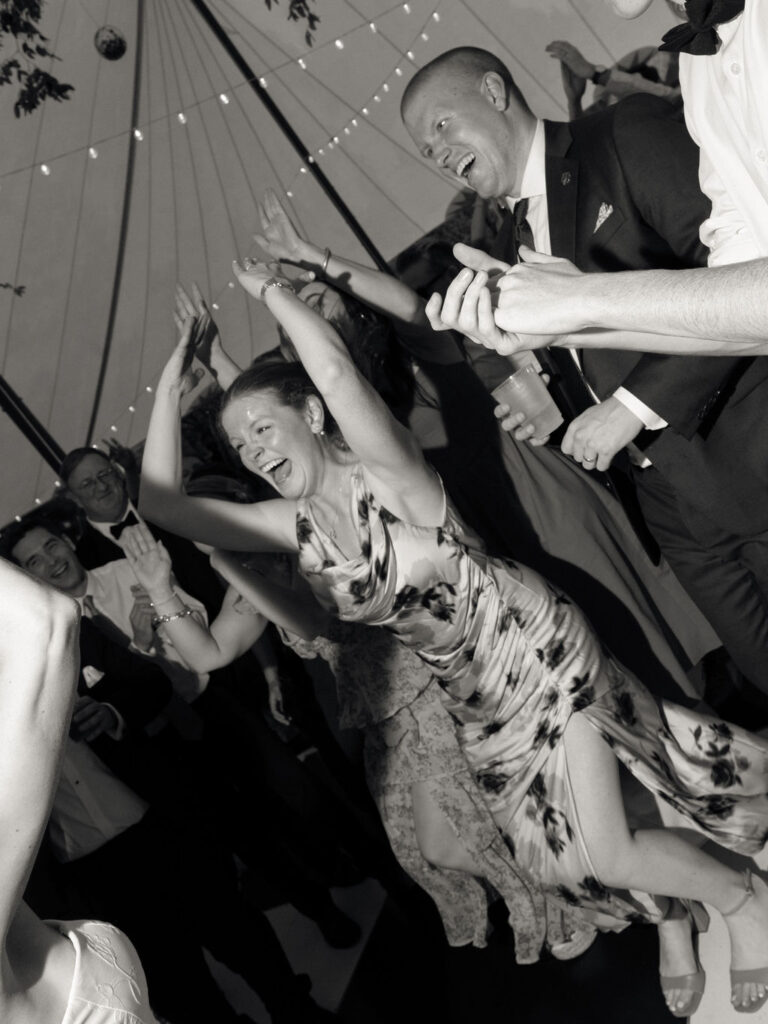 Black and white photo of guests dancing during an energetic reception