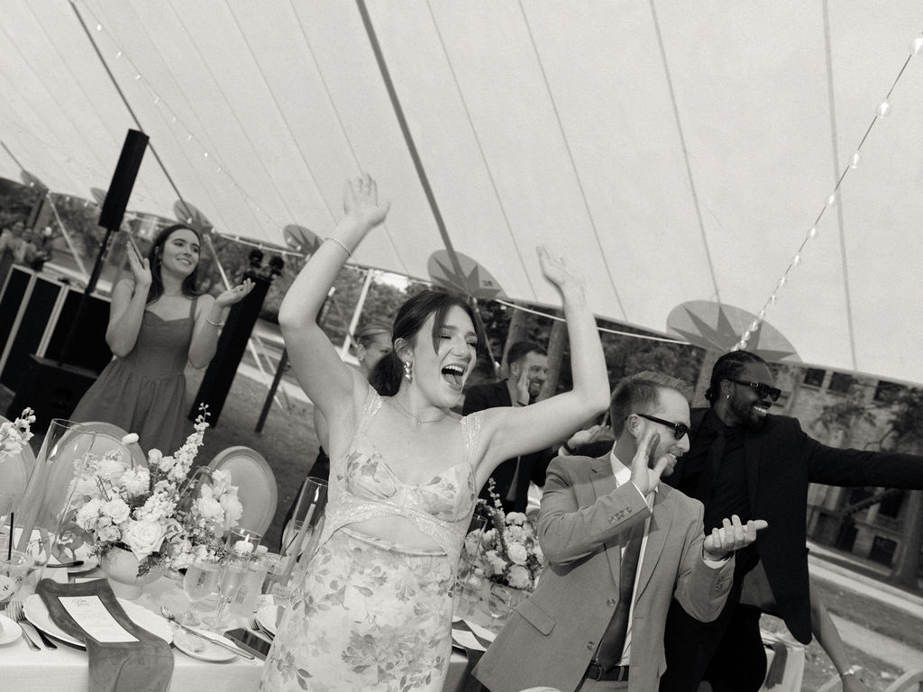 Black and white photo of guests clapping as the bride ands groom enter their reception