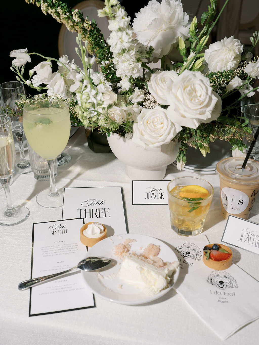 Flatlay of floral centerpiece, drinks, and dessert at wedding reception table during Saint Mary’s College tented wedding – Cynthia Mae Photo.