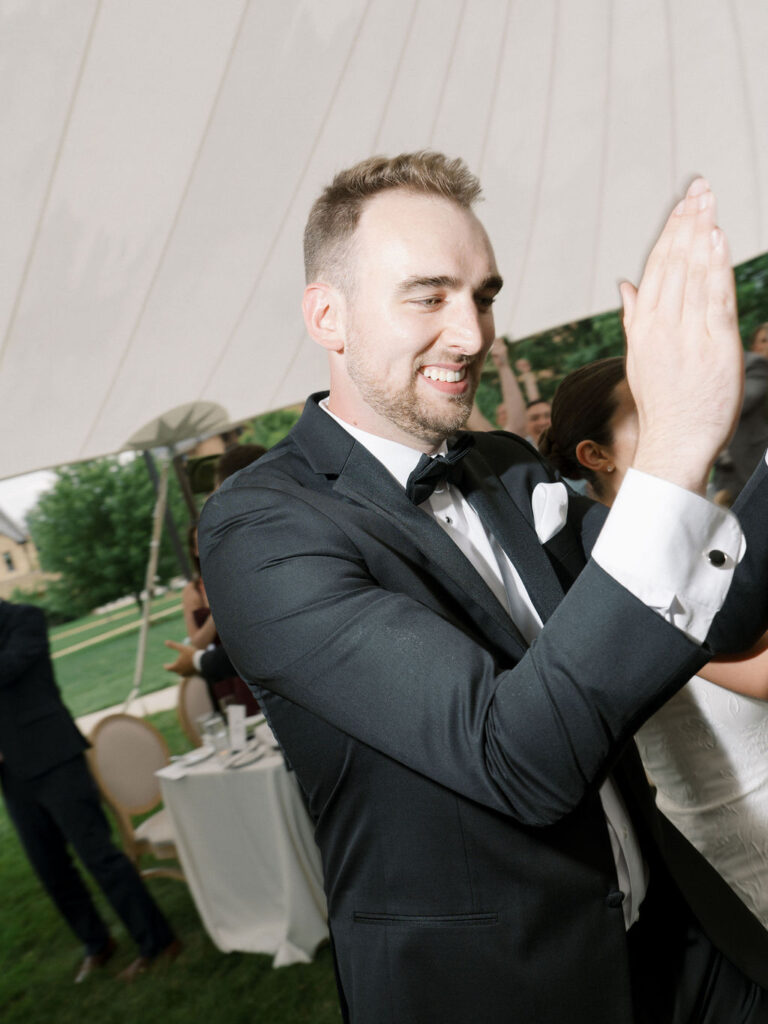Groom clapping as he enters his wedding reception