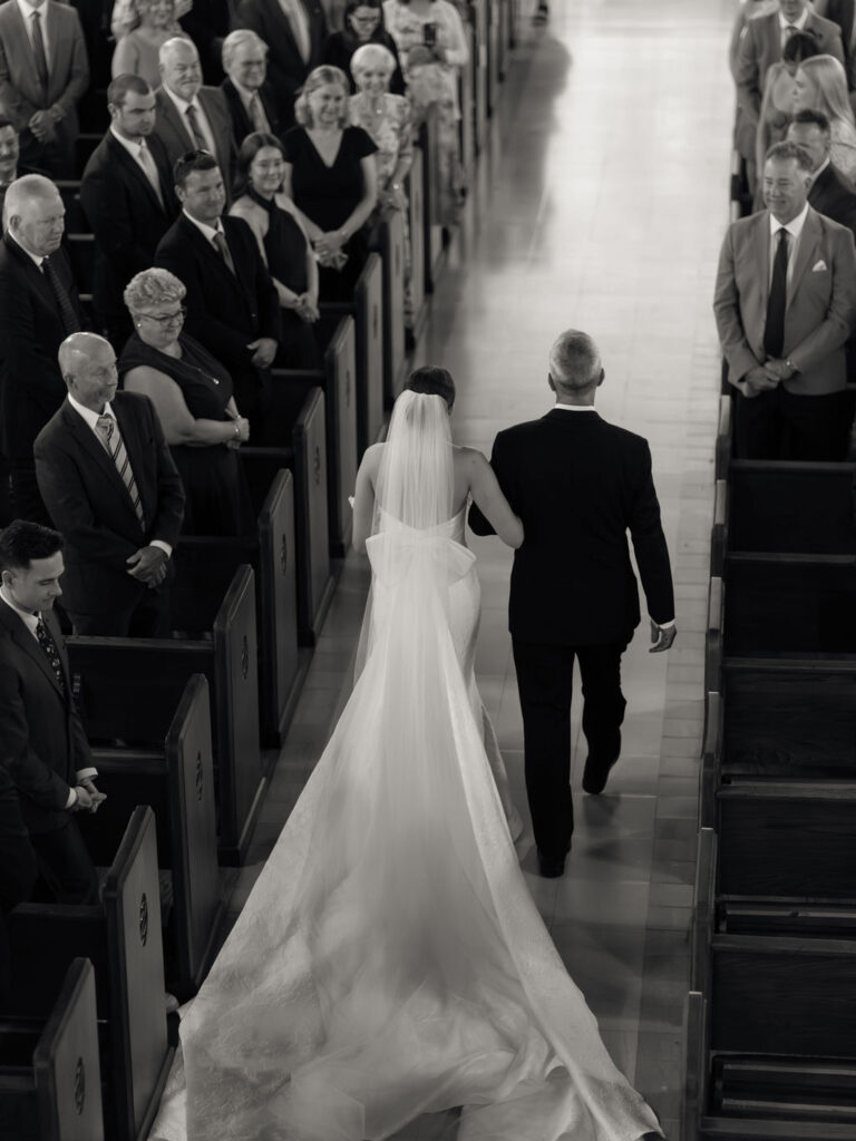 Overhead view of bride walking down the aisle with veil trailing behind during Saint Mary’s Notre Dame wedding ceremony – Cynthia Mae Photo.