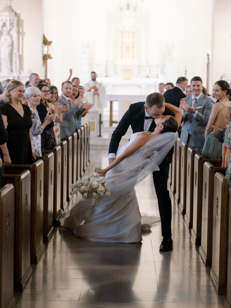 Bride and grooms end of aisle dip kiss after their Saint Mary’s Notre Dame wedding ceremony – Cynthia Mae Photo.
