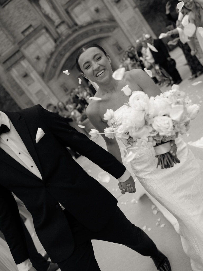 Bride smiling during petal toss outside Church of Our Lady of Loretto after Saint Mary’s Notre Dame wedding ceremony – Cynthia Mae Photo.