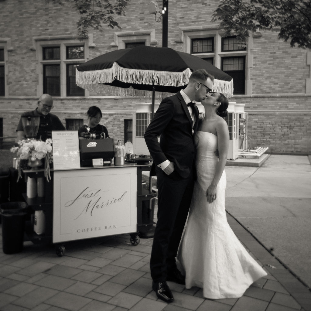 Bride and groom share a kiss in front of Clique Coffee Catering espresso bar during cocktail hour at Saint Mary’s Notre Dame wedding – Cynthia Mae Photo.