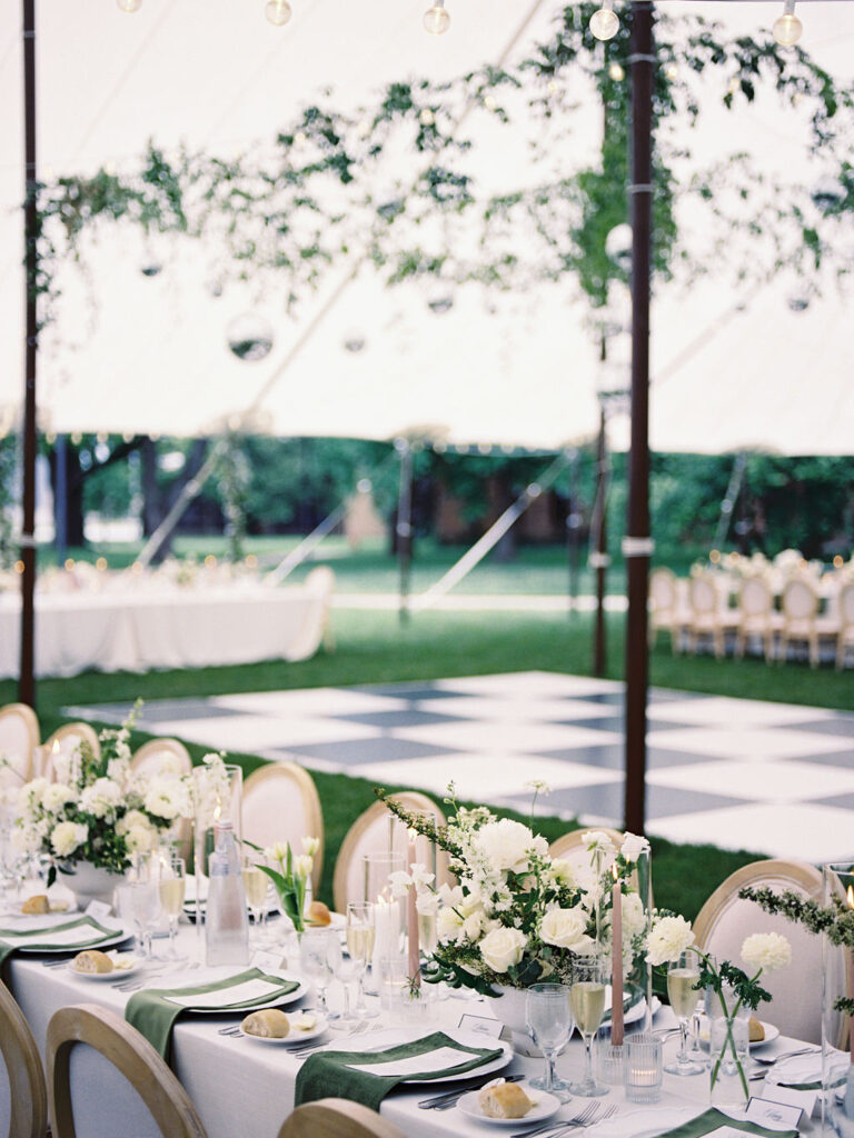 Elegant tented reception setup behind Le Mans Hall featuring white florals, greenery, and a black-and-white checkerboard dance floor – Cynthia Mae Photo.