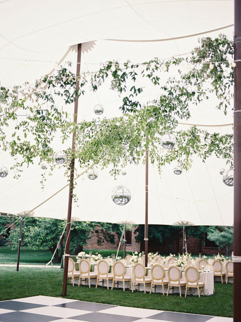 Elegant tented reception setup behind Le Mans Hall featuring white florals, greenery, and a black-and-white checkerboard dance floor – Cynthia Mae Photo.